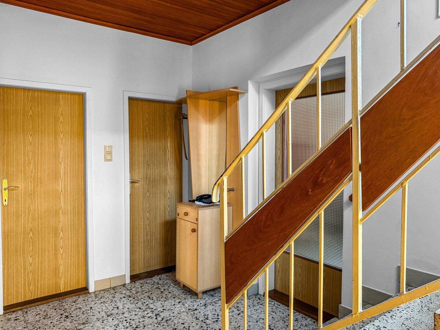 Flur mit Terrazzoboden, Holzdecke und Zugang zu mehreren Zimmern.