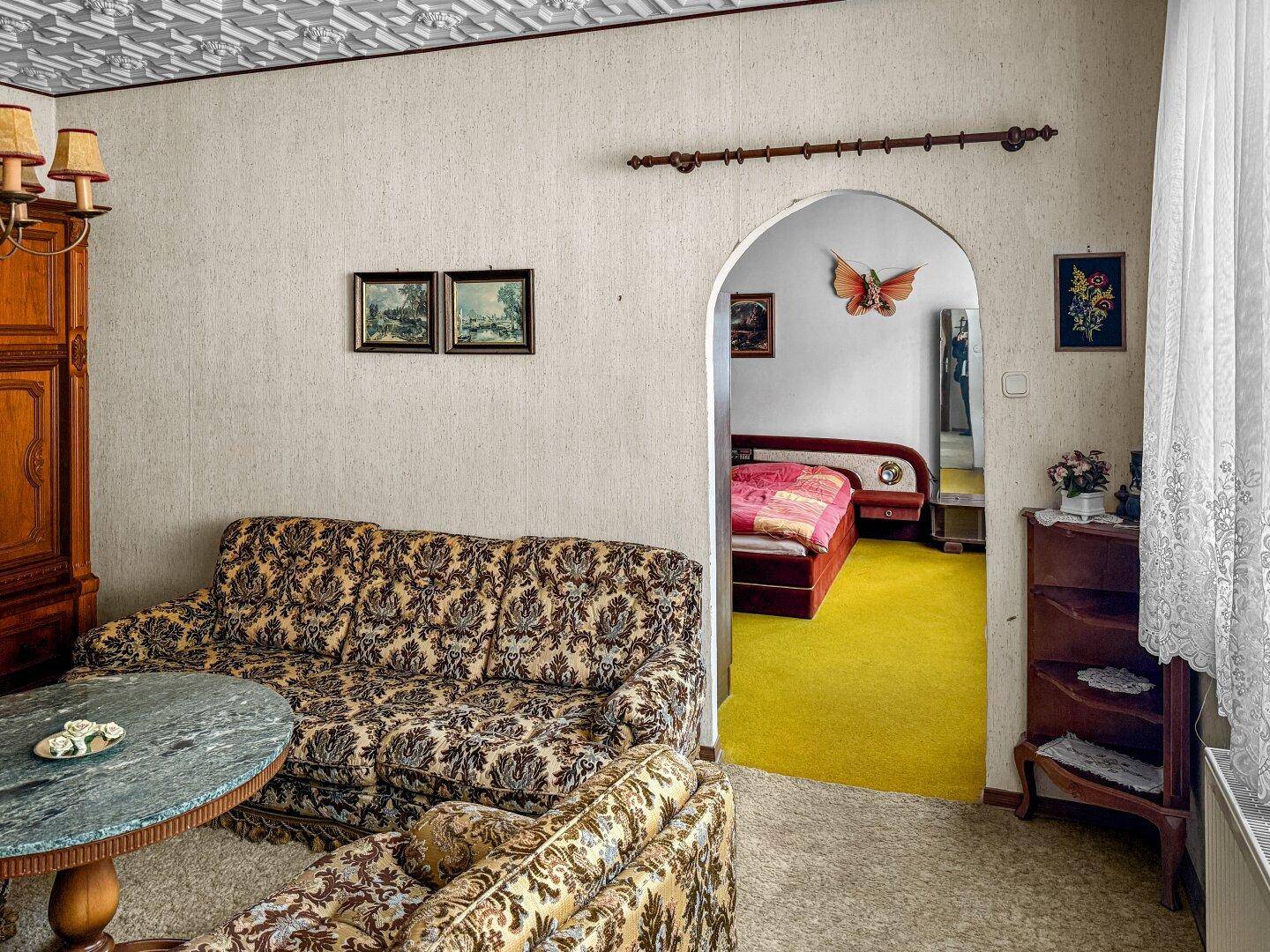 Wohnzimmer mit Blick auf ein angrenzendes Schlafzimmer durch einen Rundbogen.