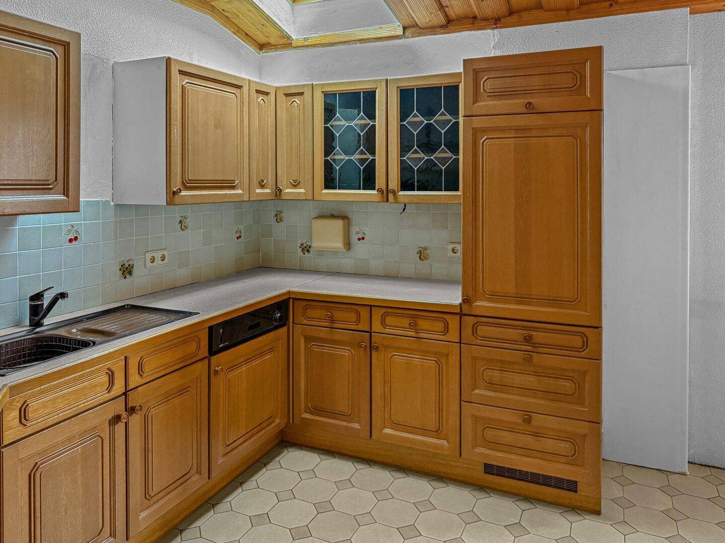 Dachgeschossküche mit Holzschränken, Fliesenrückwand und Dachfenster für natürliches Licht.