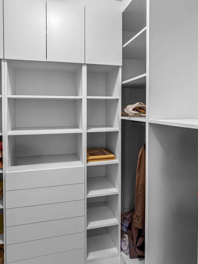 Begehbarer Kleiderschrank mit weißen Regalen und Schubladen für organisierte Aufbewahrung.