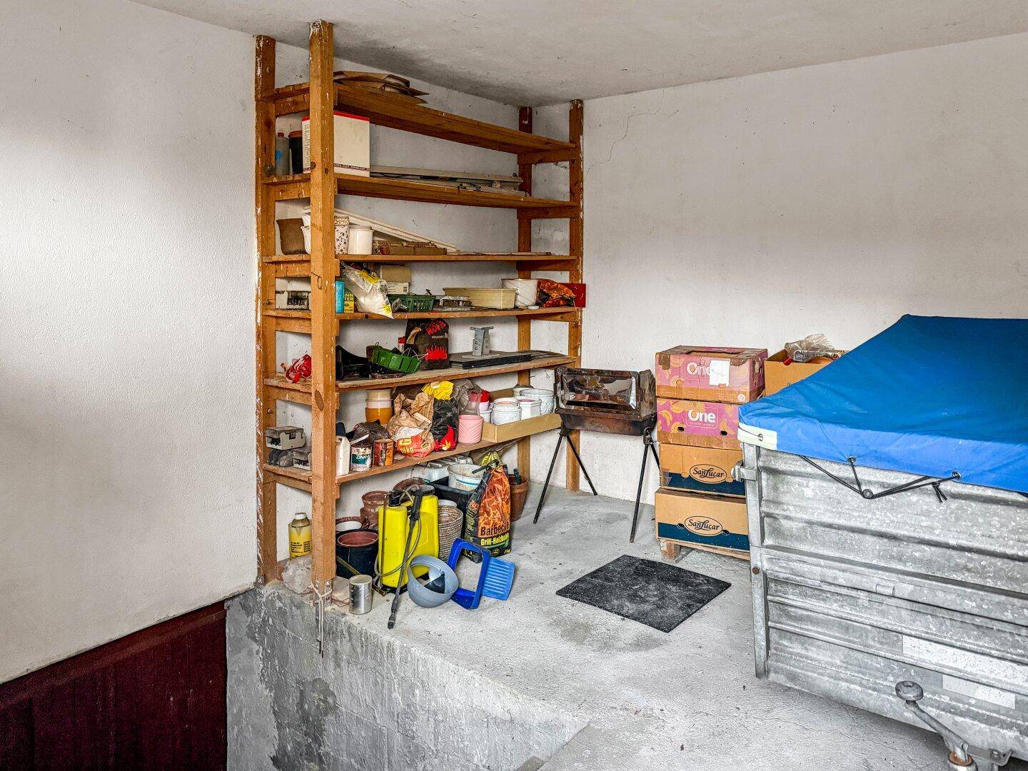 Abstellraum im Keller mit Holzregalen und verschiedenen Haushaltsgegenständen.