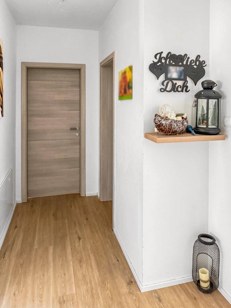 Heller Flur mit Laminatboden, Holztüren und dekorativer Wandgestaltung.