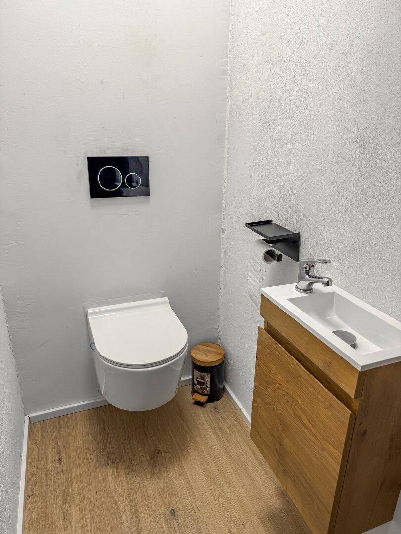 Modernes Gäste-WC mit wandhängender Toilette und kleinem Waschtisch.