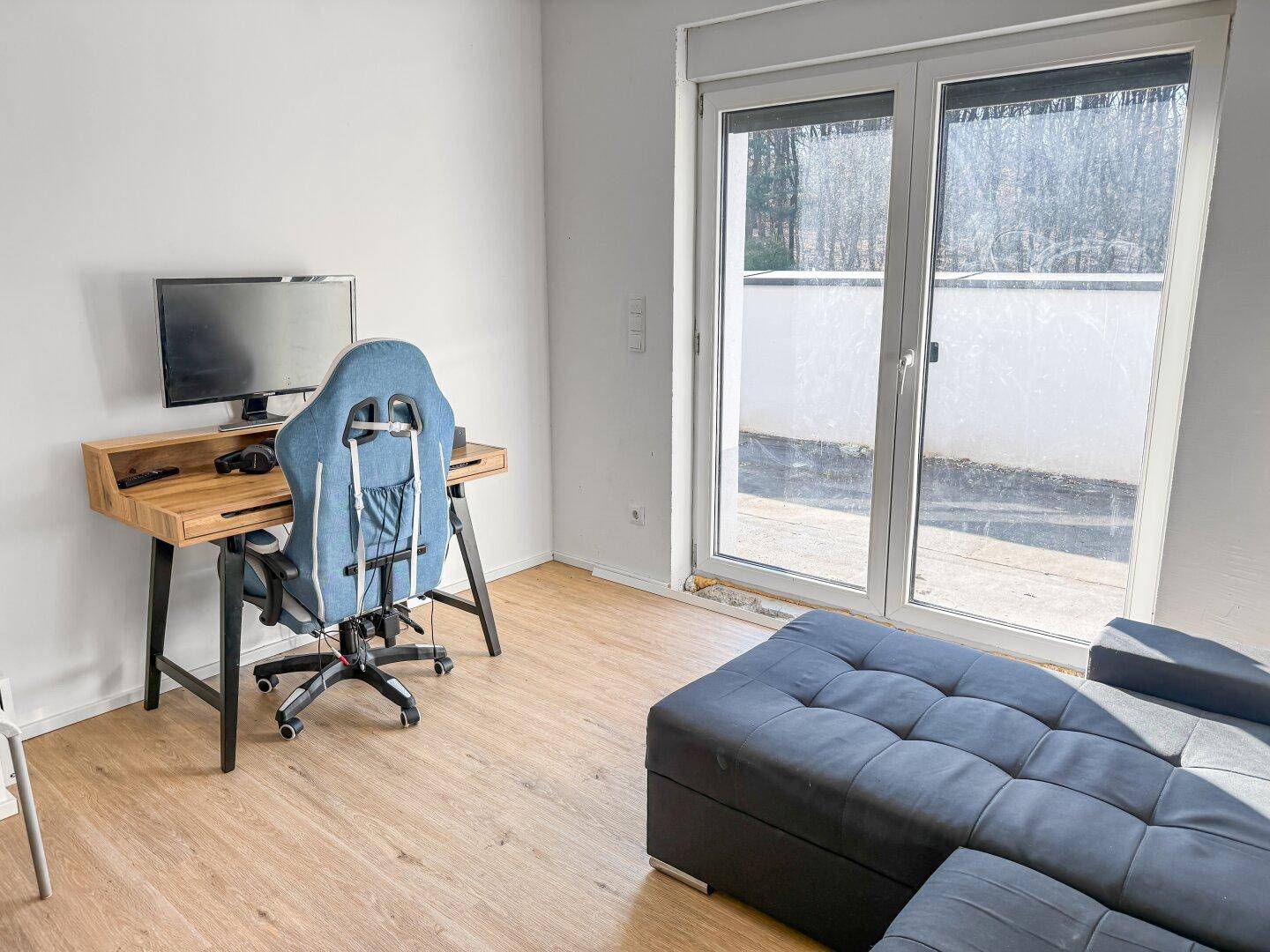 Arbeitszimmer mit Schreibtisch, Bürostuhl und Zugang zur Terrasse.