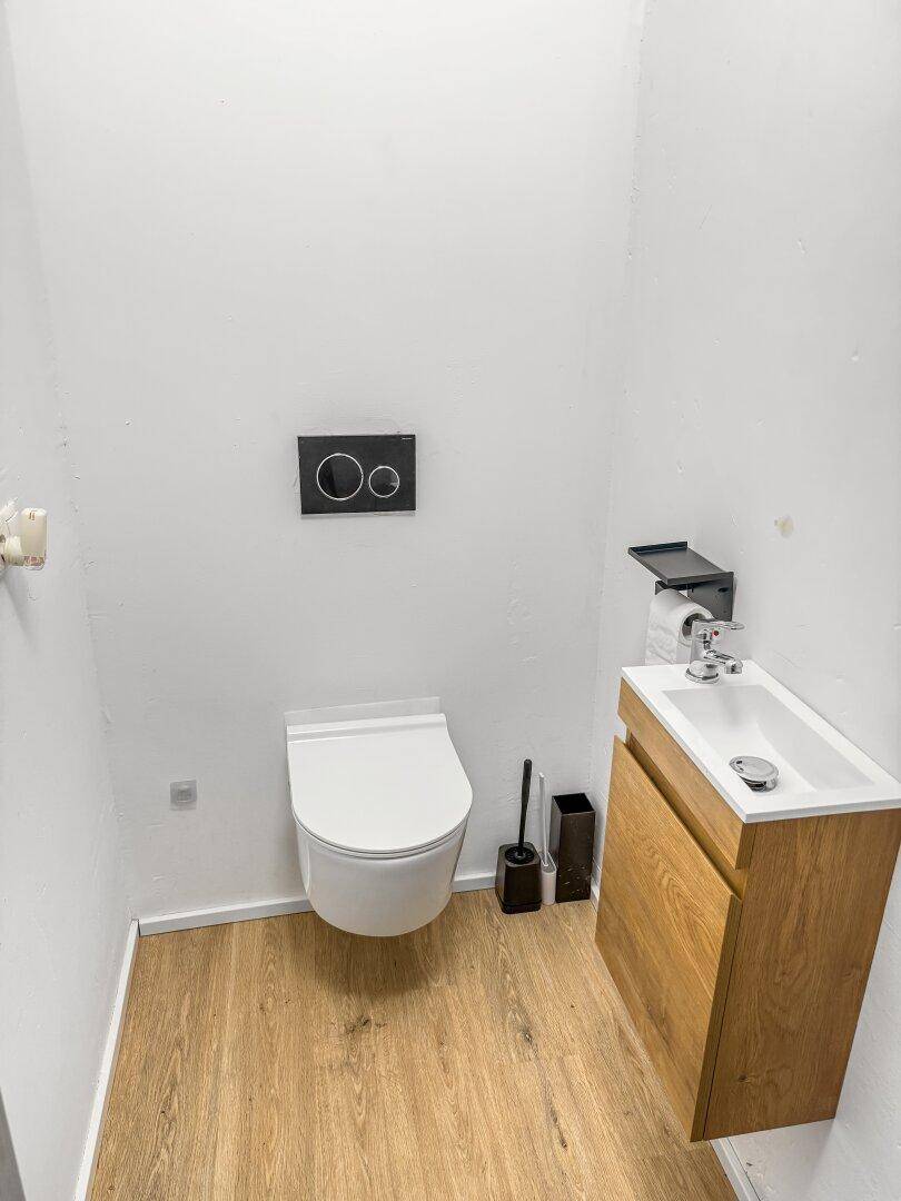Modernes Gäste-WC mit wandhängender Toilette und kleinem Waschtisch.