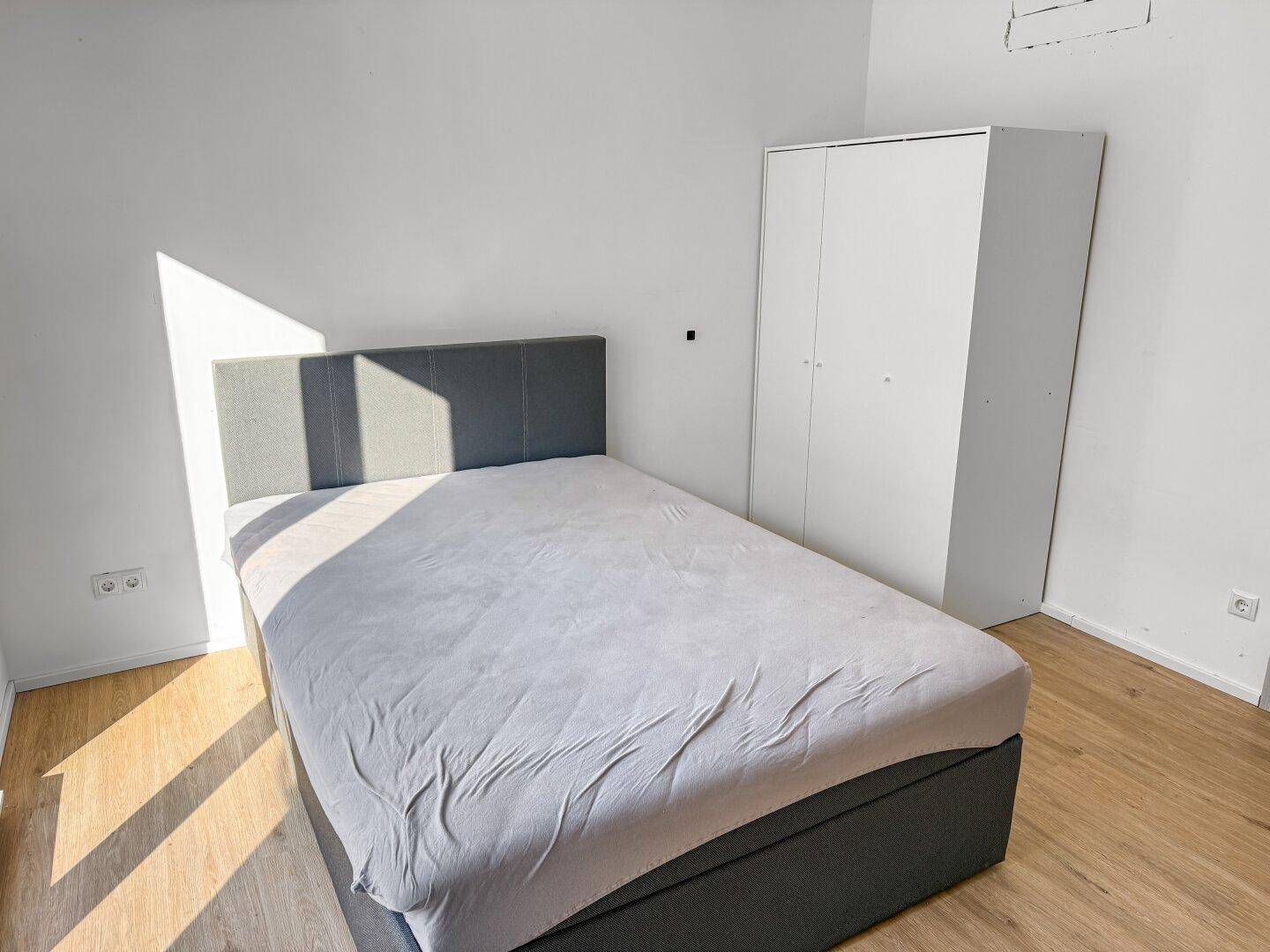 Helles Schlafzimmer mit Einzelbett, Kleiderschrank und viel Tageslicht.
