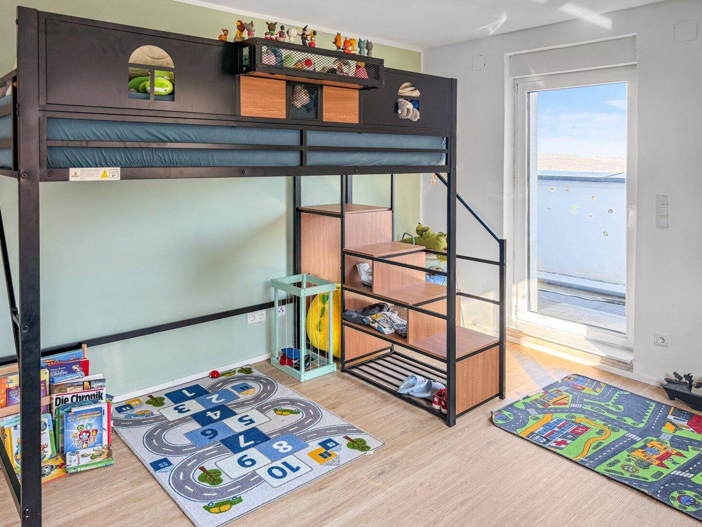Kinderzimmer mit Hochbett, Spielteppichen und Zugang zur Terrasse.