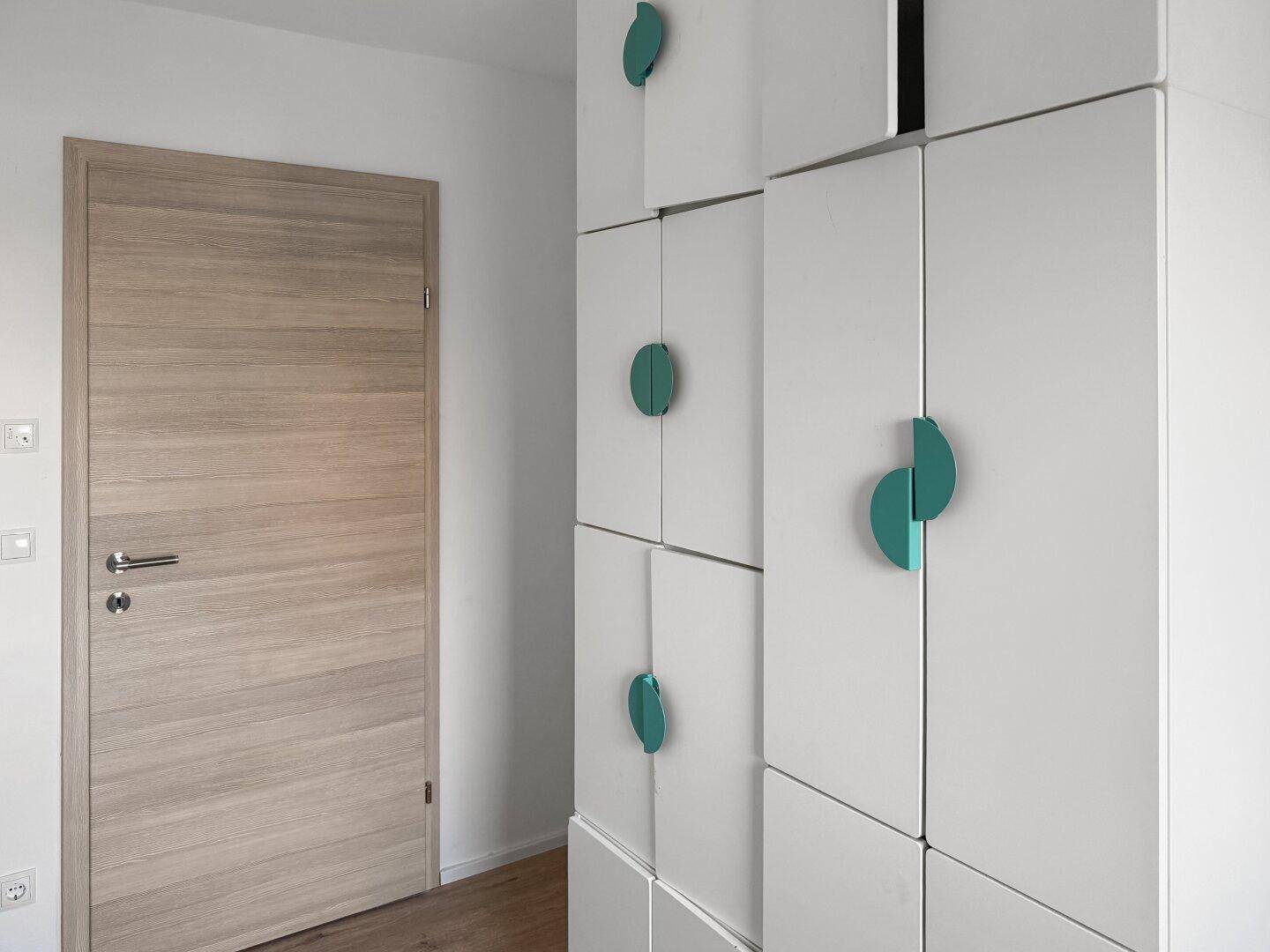Heller Flur mit weißen Einbauschränken und Holztür.