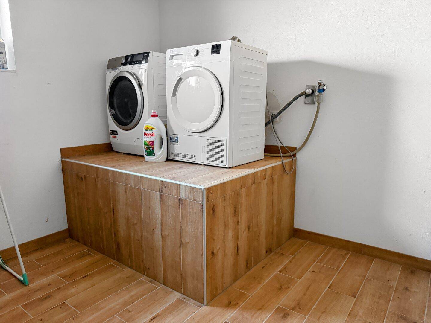 Hauswirtschaftsraum mit Waschmaschine, Trockner und gefliestem Boden.