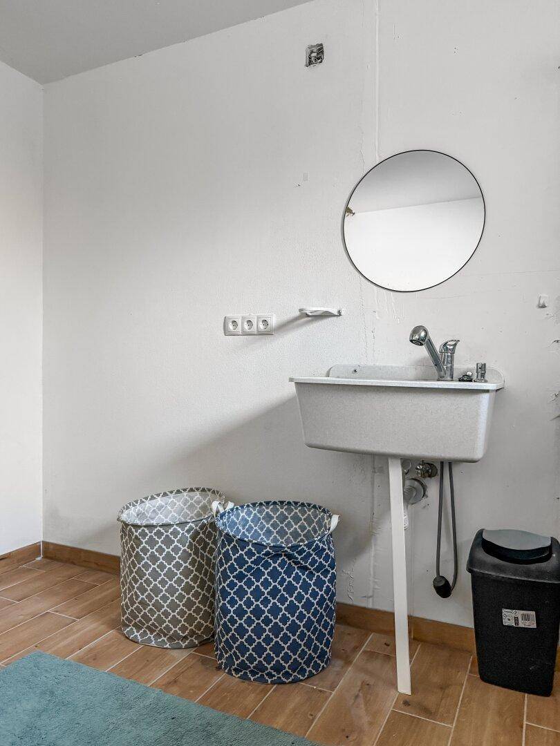 Hauswirtschaftsraum mit Waschbecken, Spiegel und Wäschekörben.