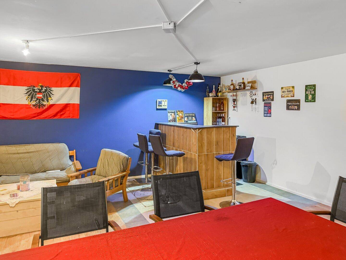 Gemütlicher Partyraum im Keller mit Bar, Sitzgelegenheiten und österreichischer Flagge.