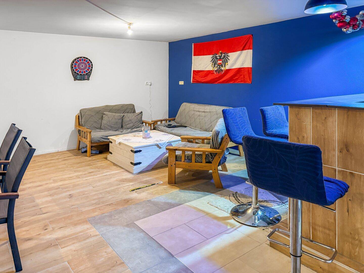 Geräumiger Kellerraum mit Bar, Sitzgelegenheiten und Laminatboden.