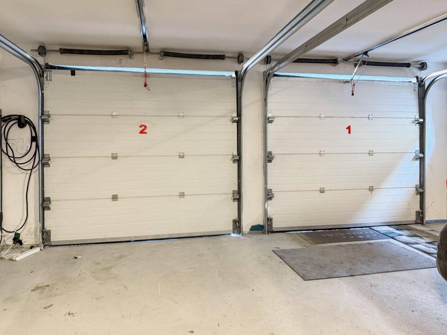 Doppelgarage mit zwei Sektionaltoren und EV-Ladestation.