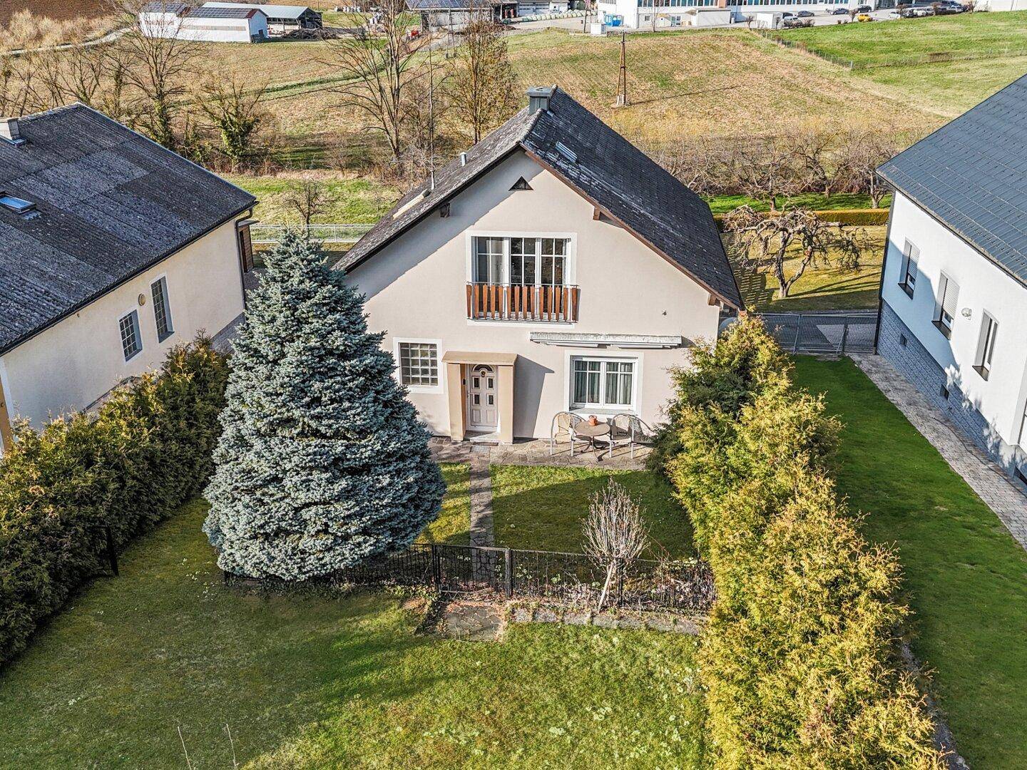 Luftaufnahme des Einfamilienhauses mit gepflegtem Garten und angrenzenden Grundstücken in ländlicher Umgebung.