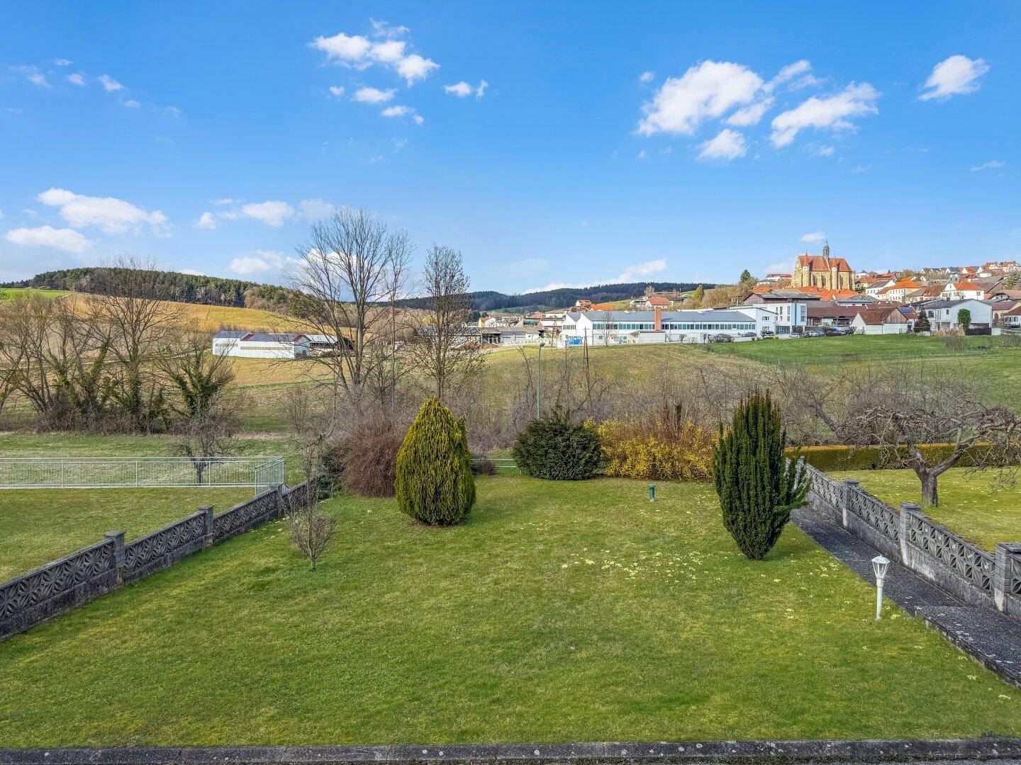 Großer Garten mit Rasenfläche und Blick auf die umliegende Landschaft und ein Dorf in der Ferne.