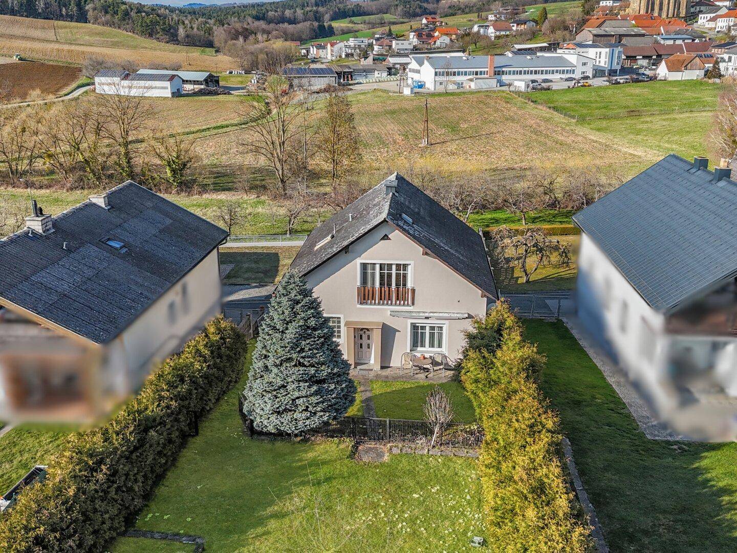Luftaufnahme des Einfamilienhauses mit gepflegtem Garten und angrenzenden Grundstücken in ländlicher Umgebung.