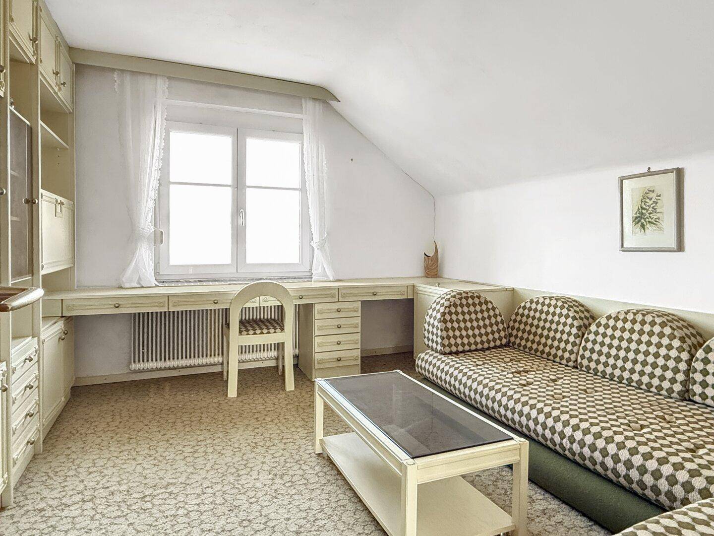Arbeitszimmer im Dachgeschoss mit Schrägen, Einbauschränken und Schreibtisch, hell und funktional.