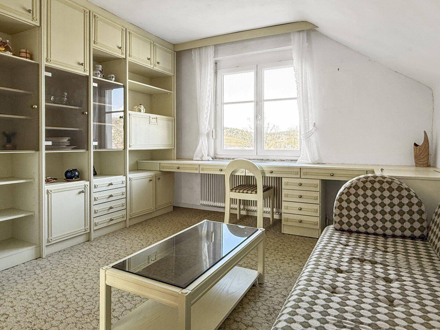 Arbeitszimmer im Dachgeschoss mit Schrägen, Einbauschränken und Schreibtisch, hell und funktional.