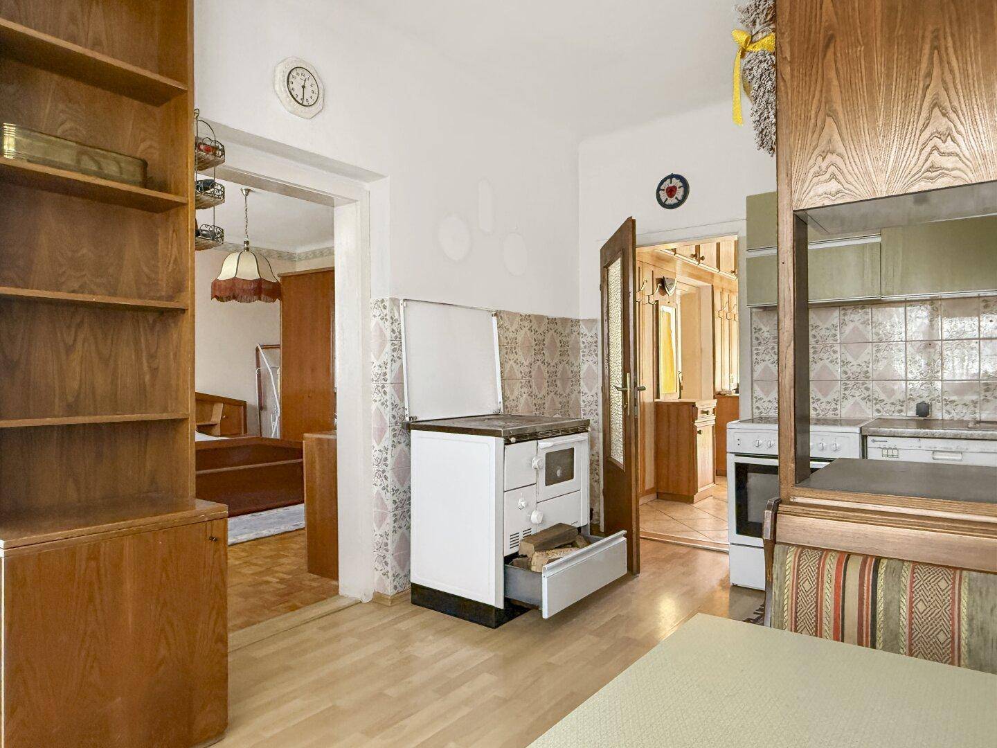 Küche mit Holzofen und Blick in das angrenzende Schlafzimmer.