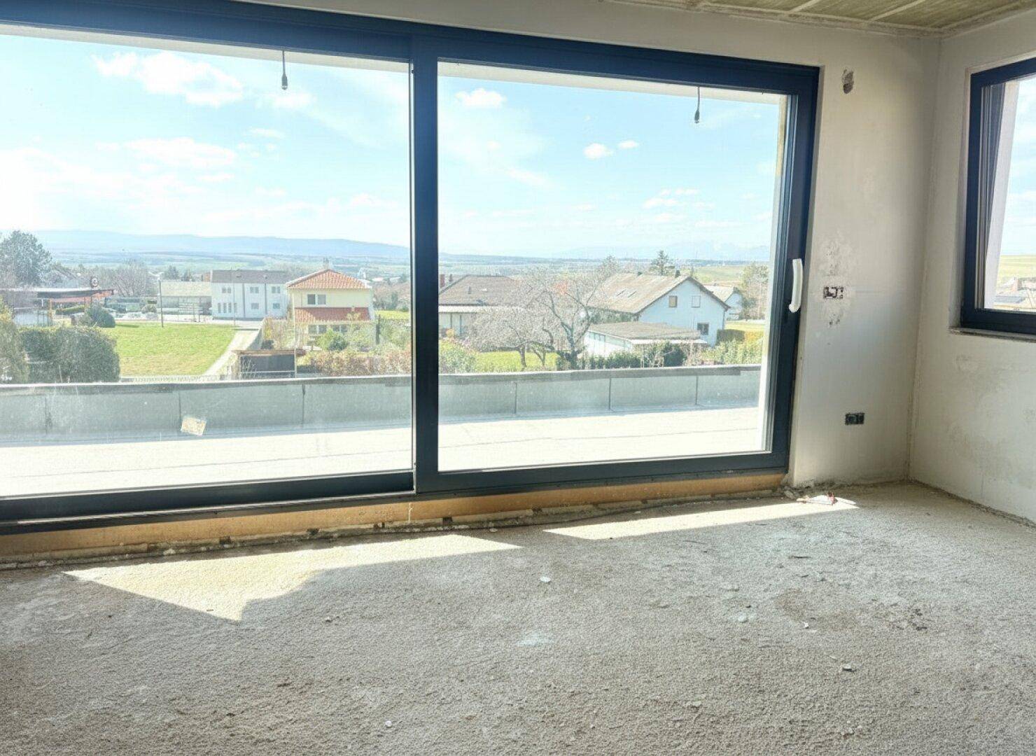 Rohbau-Raum mit großen Schiebetüren und weitem Blick über die Landschaft.