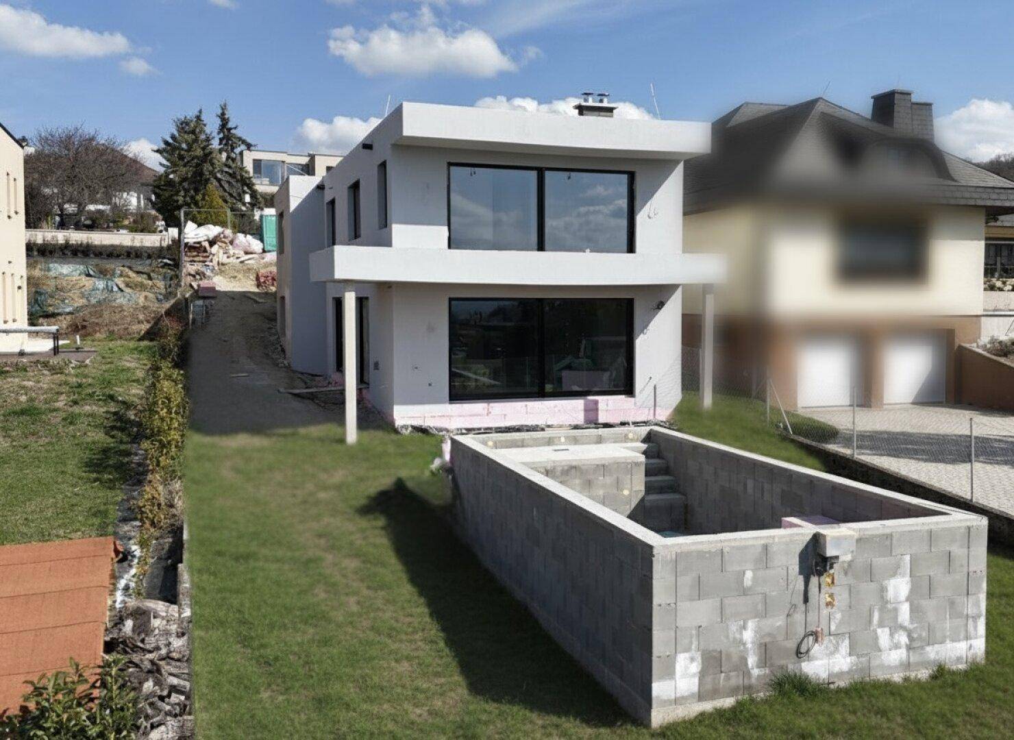 Neubau-Villa im Rohbau mit vorbereitetem Poolbereich und Garten.