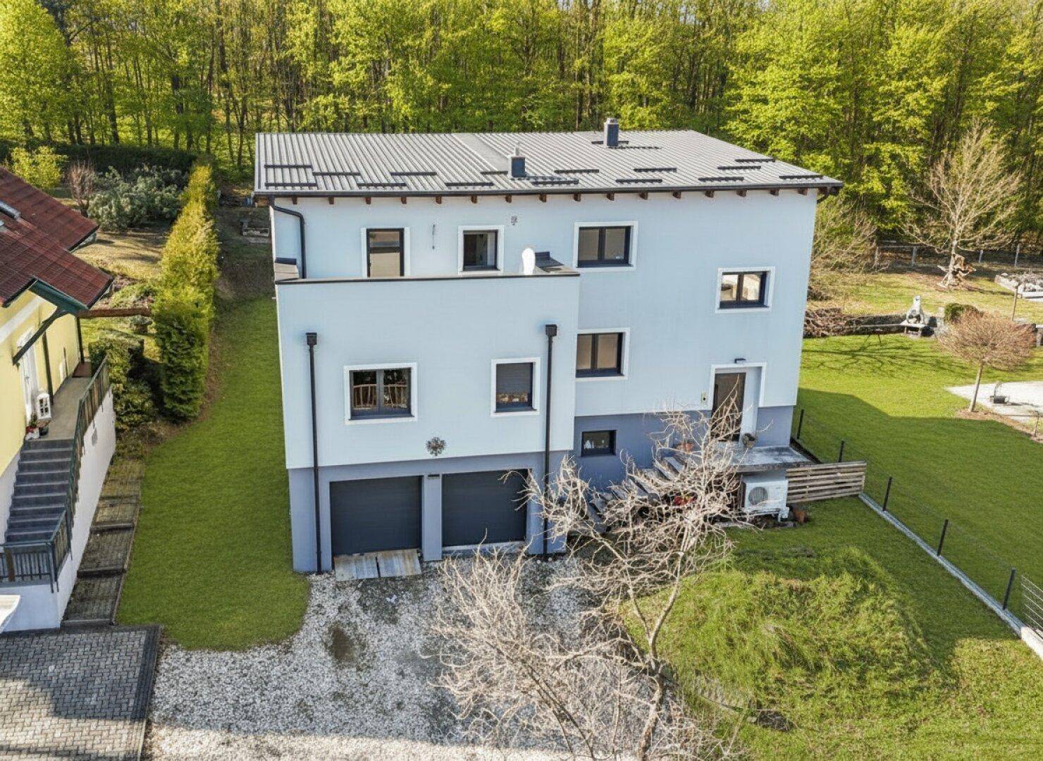 Vogelperspektive des modernen Einfamilienhauses mit großem Garten und Zufahrt zur Garage.