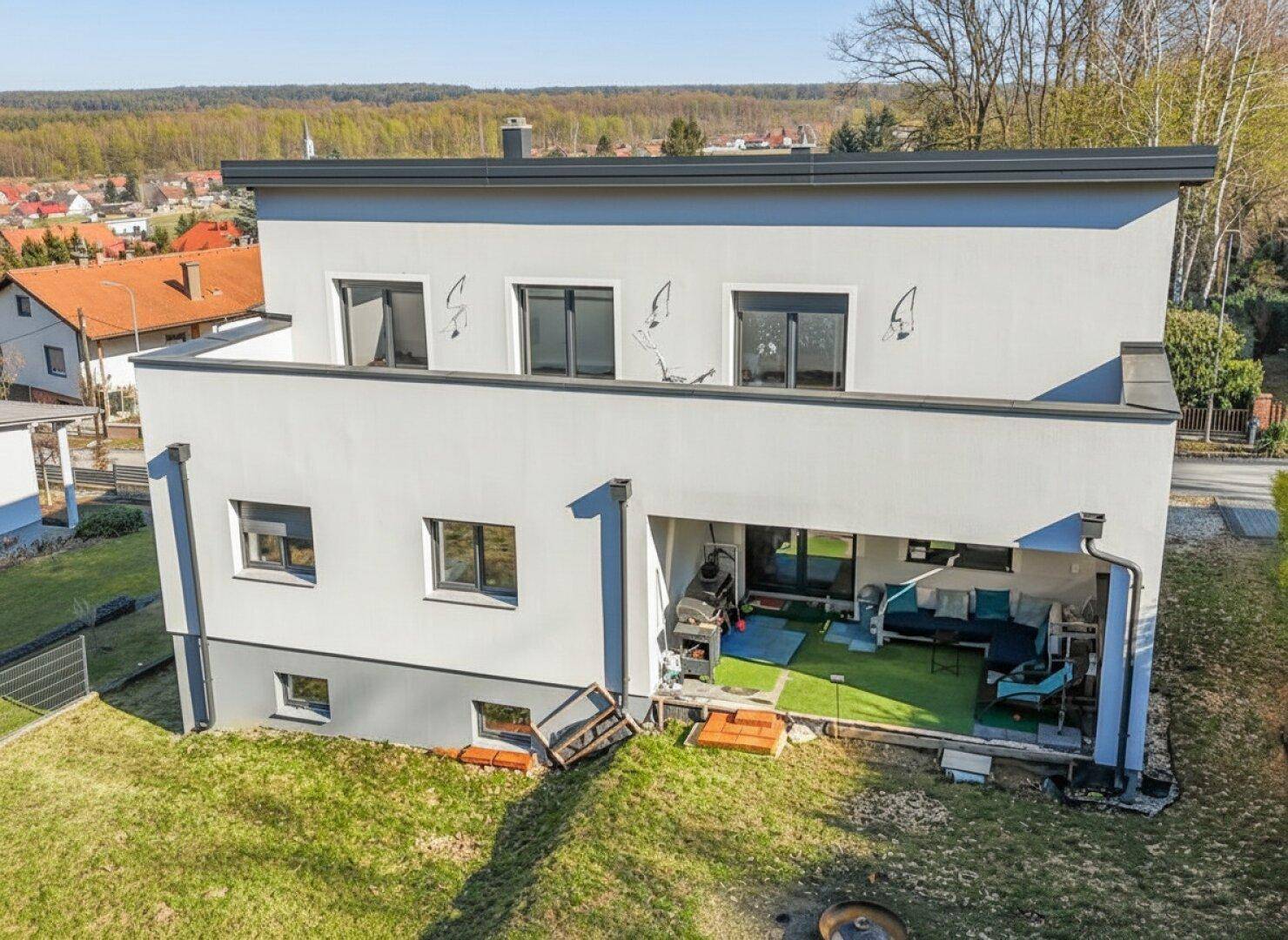 Rückseite des Hauses mit einer möblierten Terrasse und Blick ins Grüne.