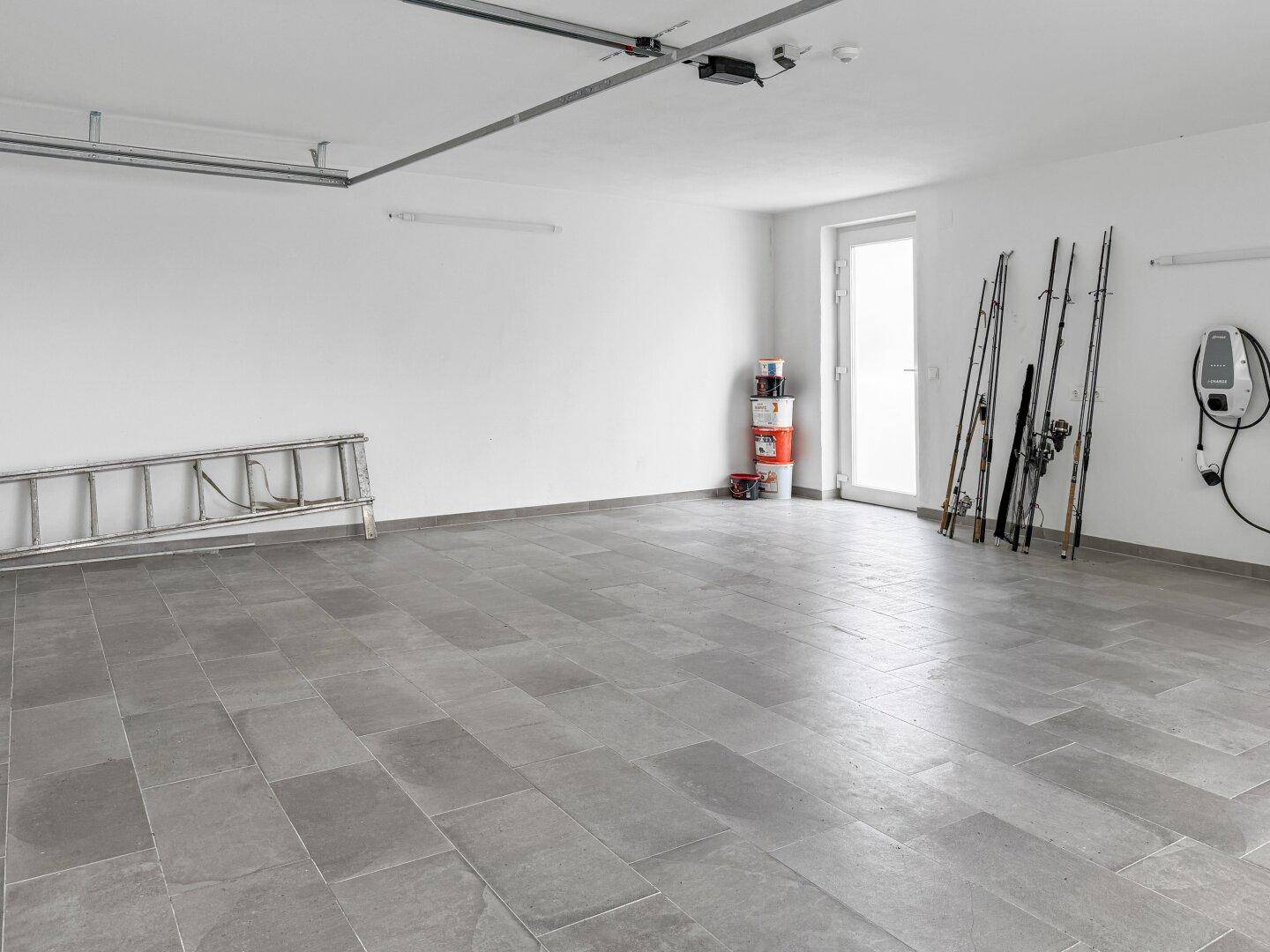 Helle Garage mit Fliesenboden und Ladestation für Elektrofahrzeuge.