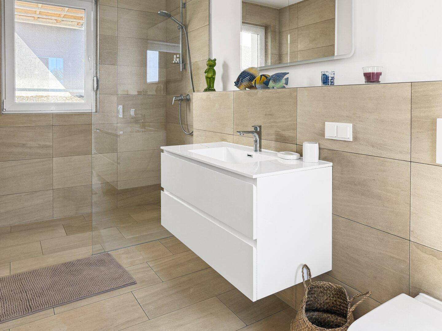 Modernes Badezimmer mit schwebendem Waschtisch, beigefarbenen Fliesen und großer Dusche.