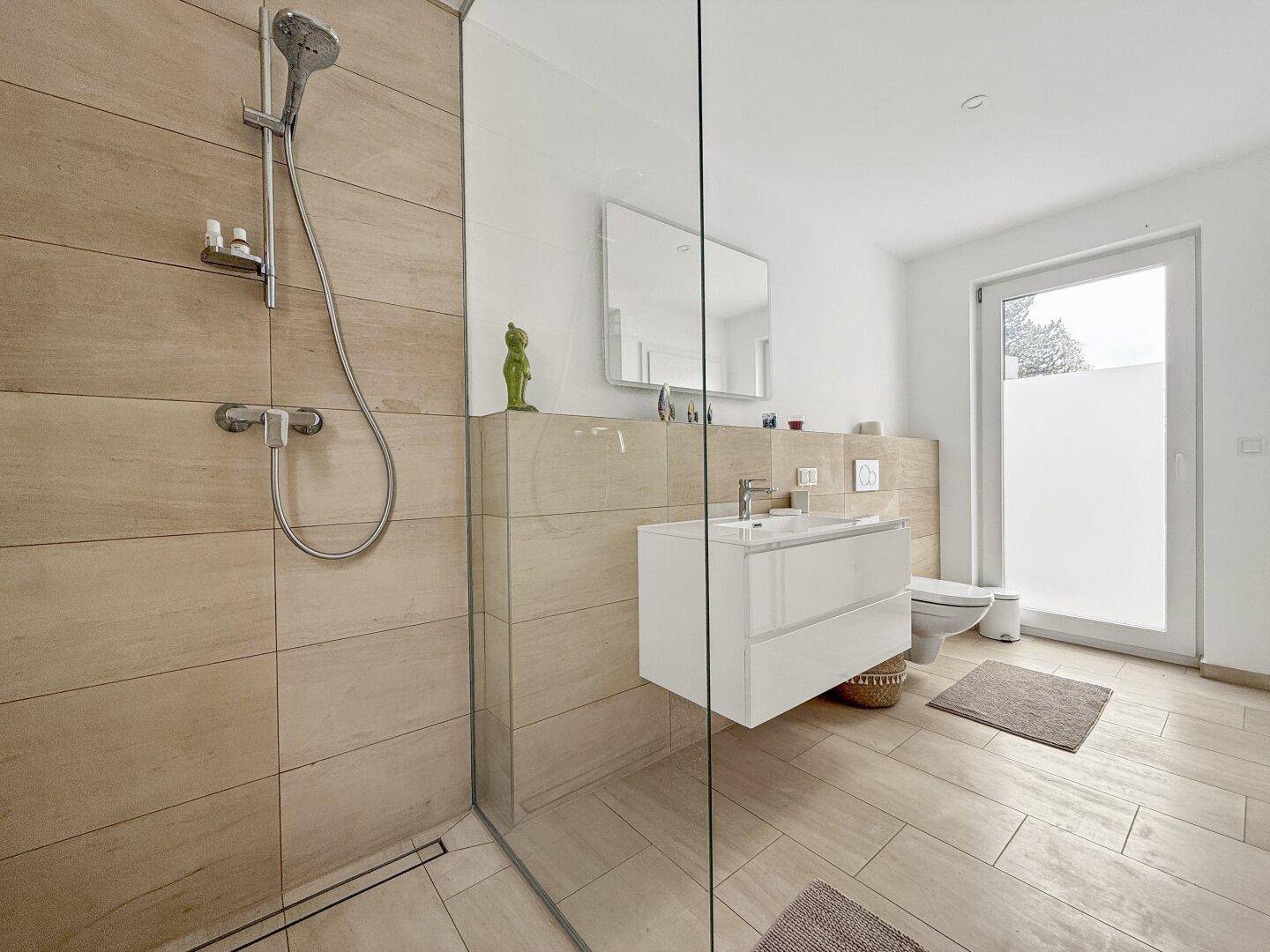 Helles Badezimmer mit begehbarer Dusche, modernen Armaturen und Zugang nach draußen.