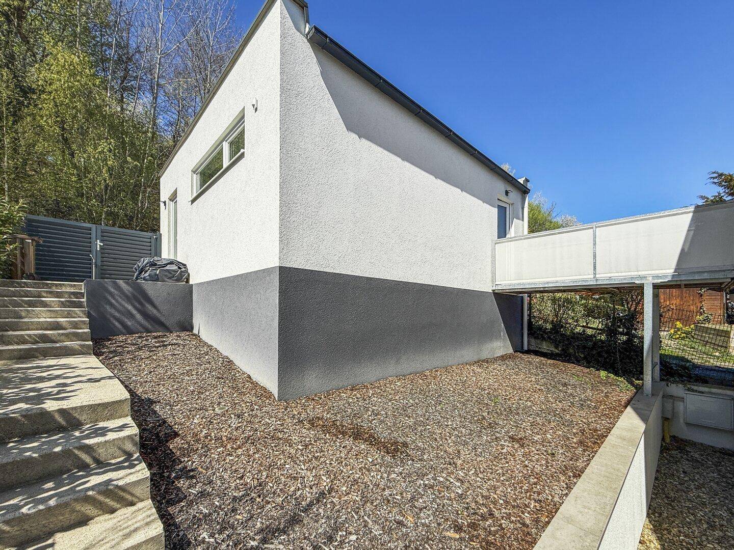 Seitliche Ansicht des modernen Hauses mit Treppenaufgang und schlichter Fassade.