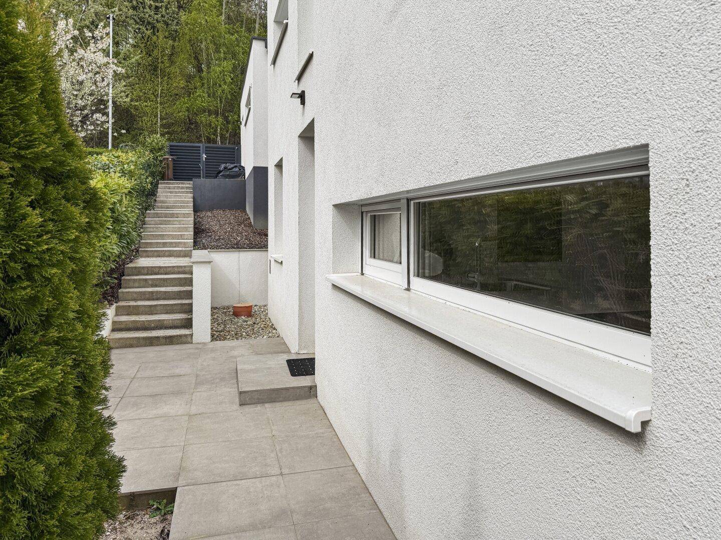 Außenbereich des Hauses mit gepflastertem Weg und moderner Fassade.
