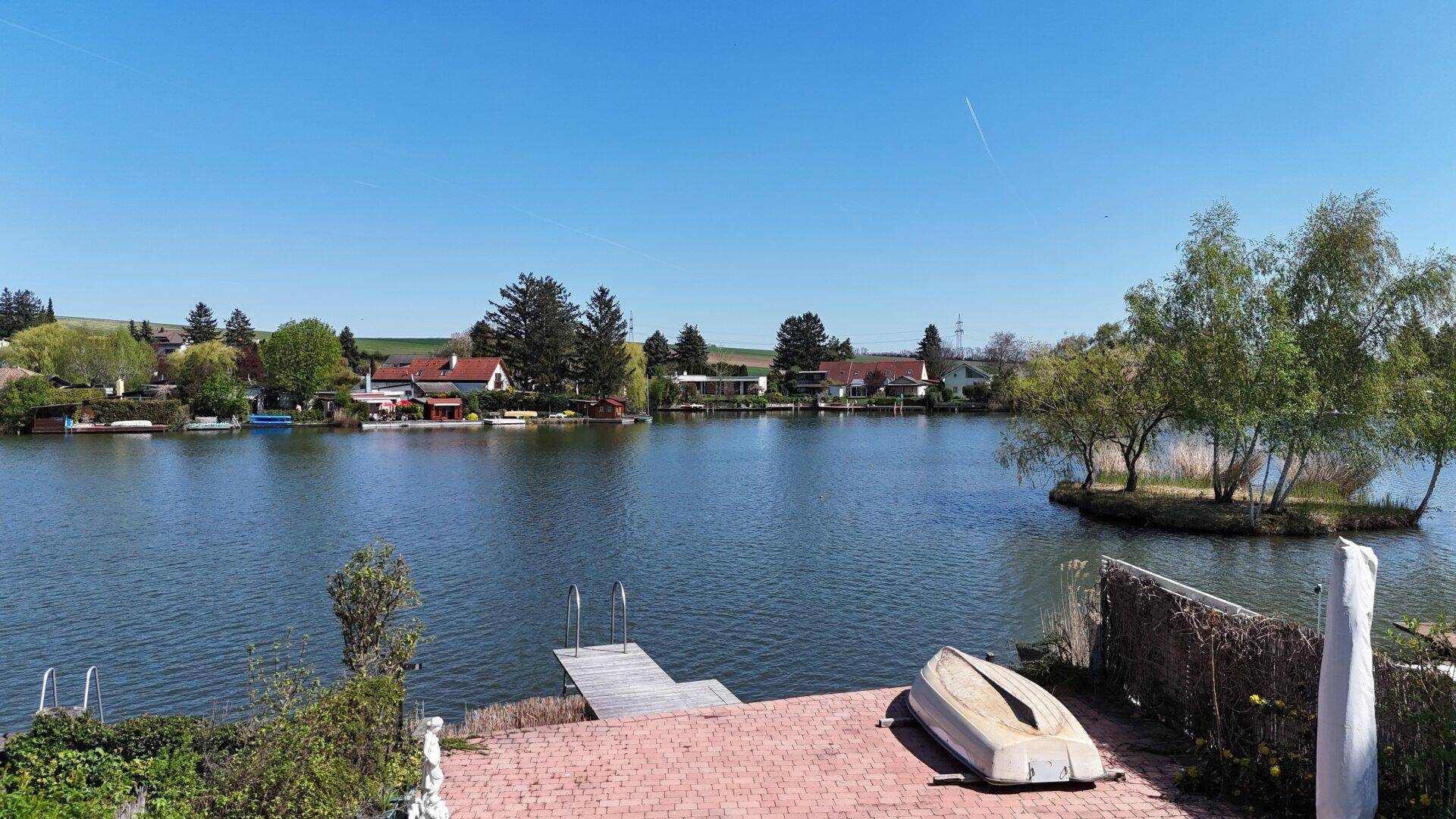 Weitläufiger Blick auf den See mit umliegenden Häusern und Bootsstegen.