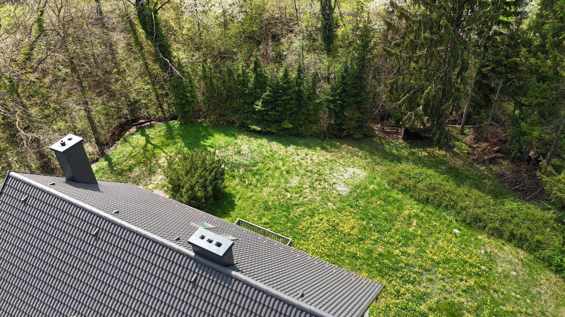 Dachansicht des Hauses mit Blick auf den weitläufigen grünen Gartenbereich.
