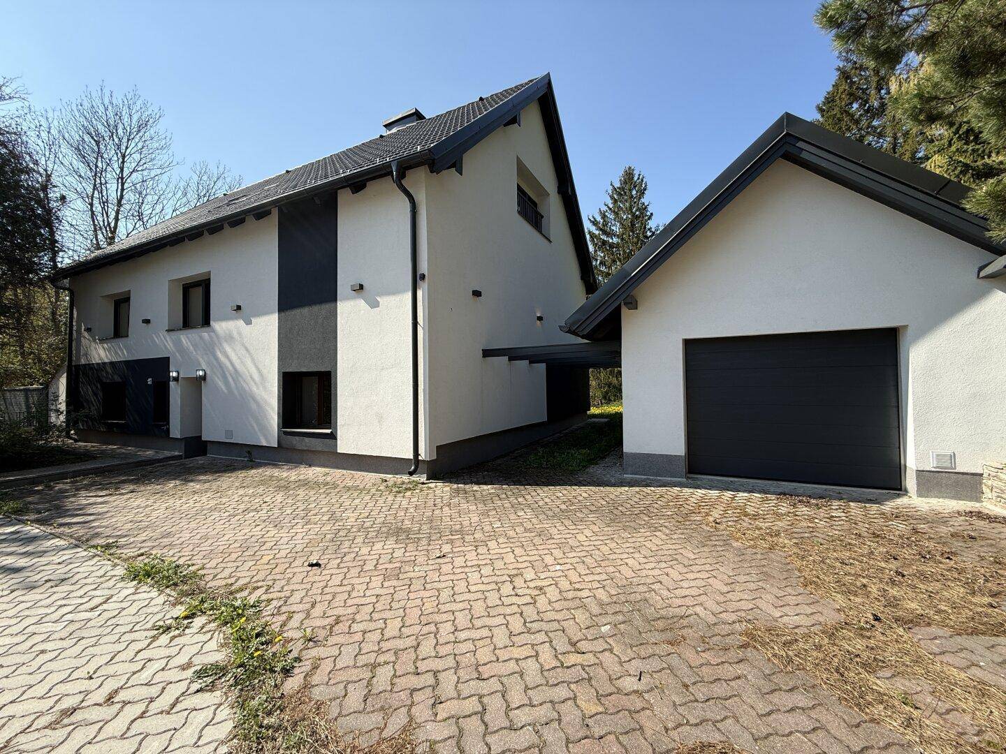 Vorderansicht des modernen Hauses mit Garage und gepflasterter Einfahrt.