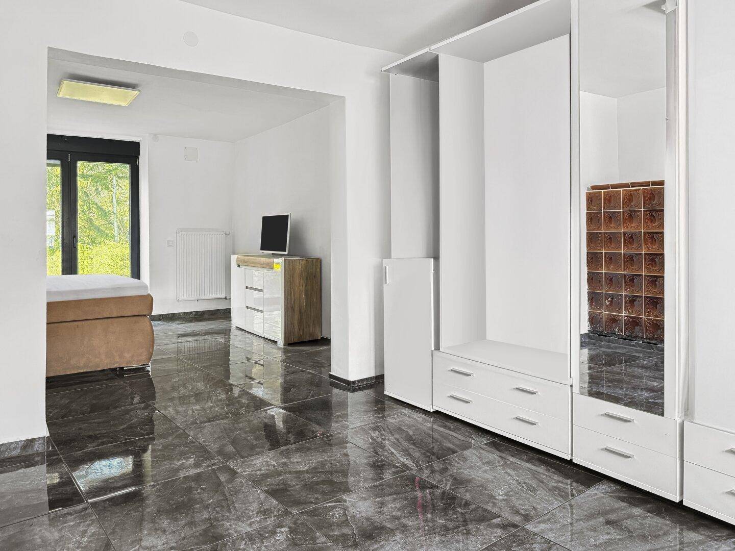 Geräumiges Schlafzimmer mit glänzendem Fliesenboden und großem Kleiderschrank.