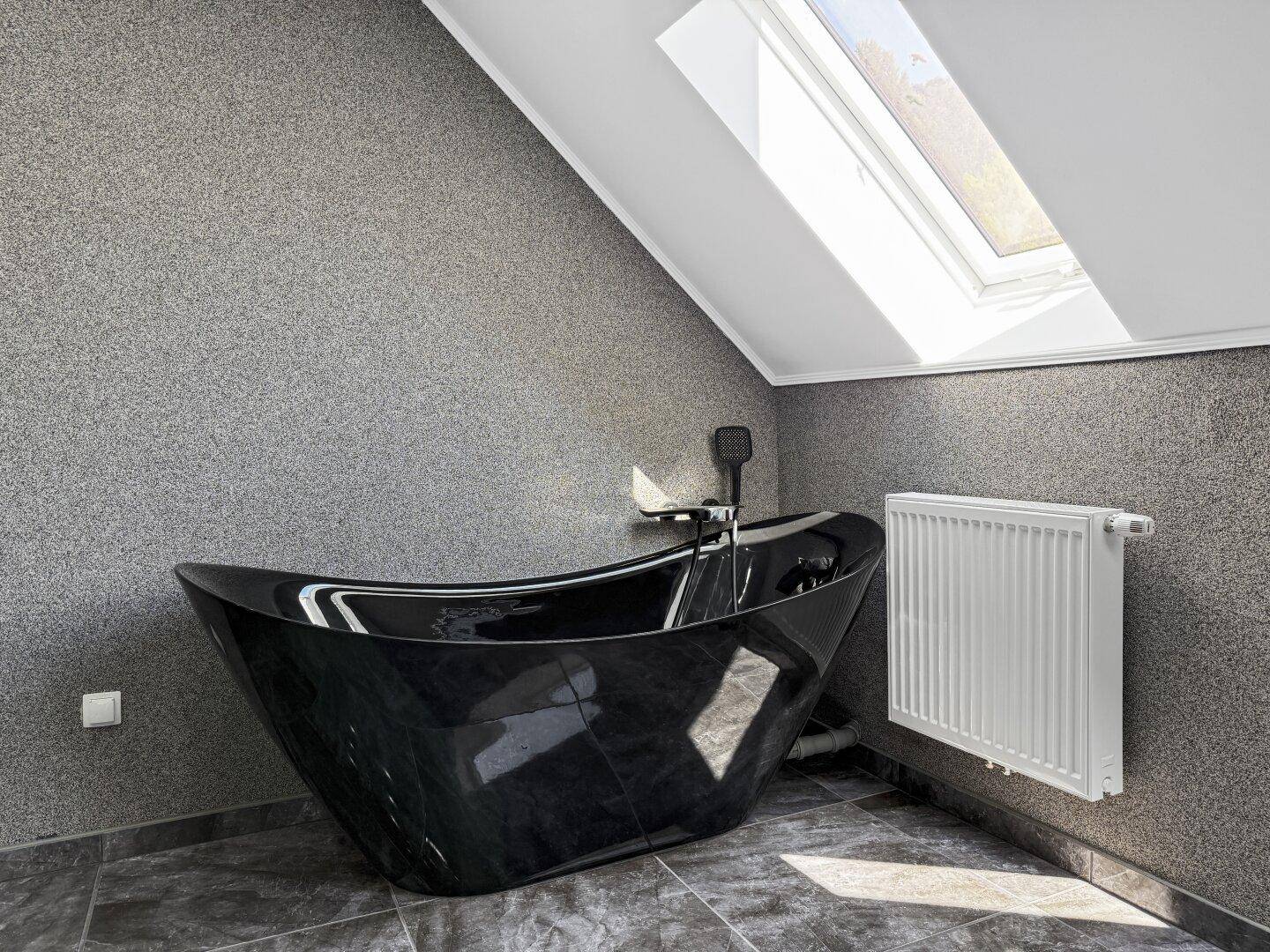Modernes Badezimmer im Dachgeschoss mit freistehender Badewanne und Dachfenster.