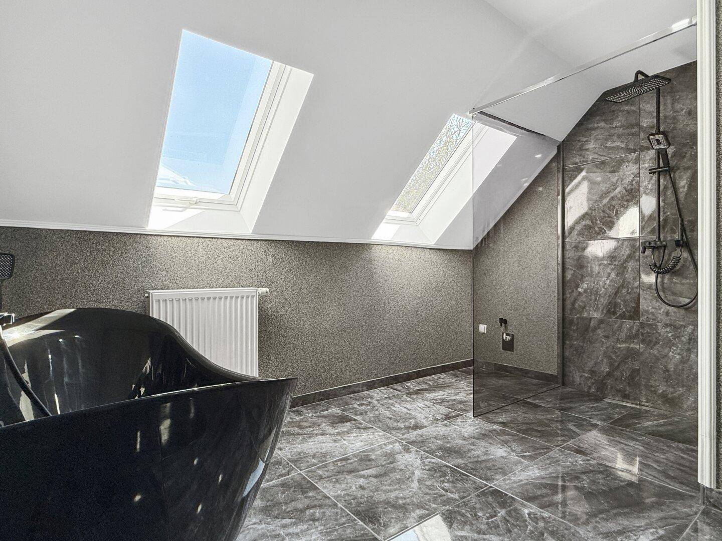 Modernes Badezimmer im Dachgeschoss mit freistehender Badewanne, Dusche und Dachfenstern.