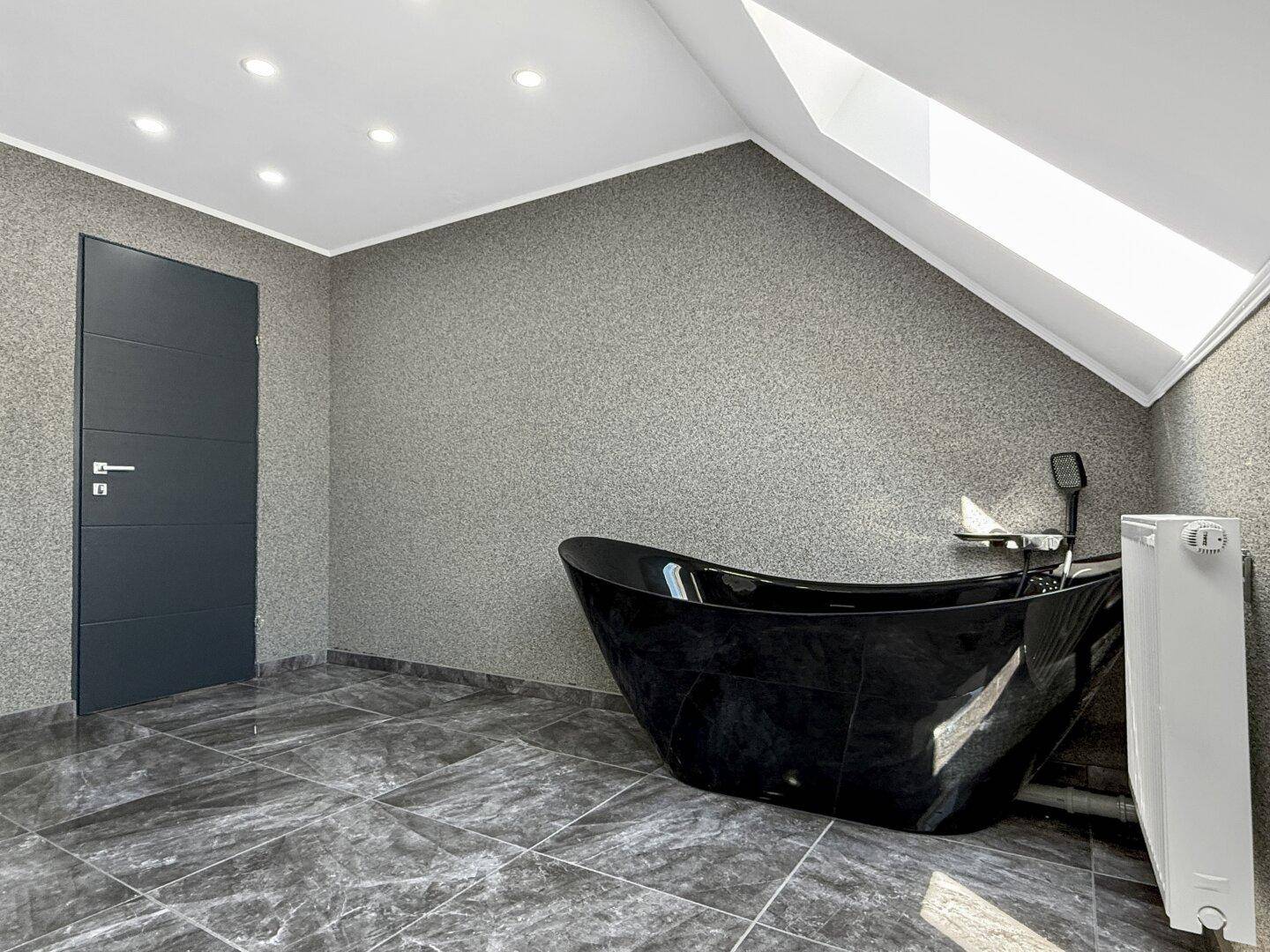 Modernes Badezimmer im Dachgeschoss mit freistehender Badewanne und moderner Tür.
