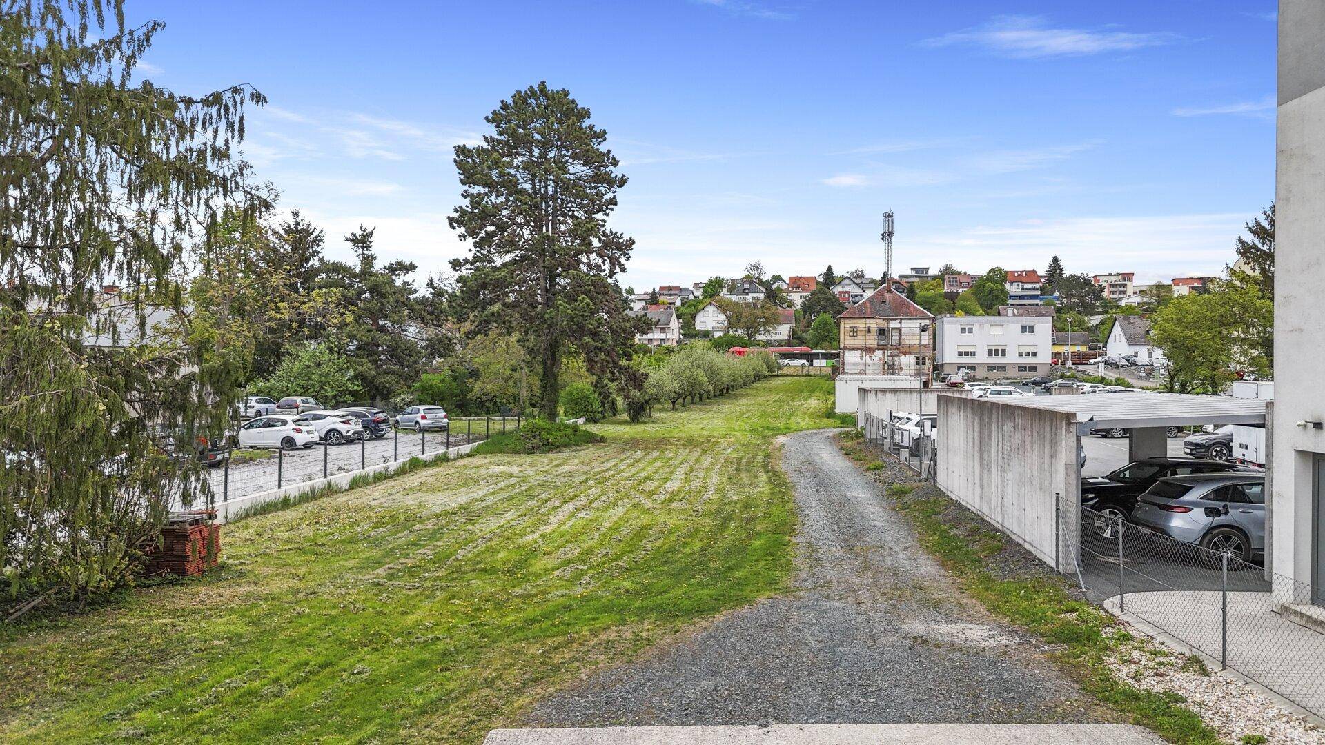Weitläufiger Hinterhof mit Grünflächen, Parkplätzen und Blick auf die umliegende Wohnbebauung.