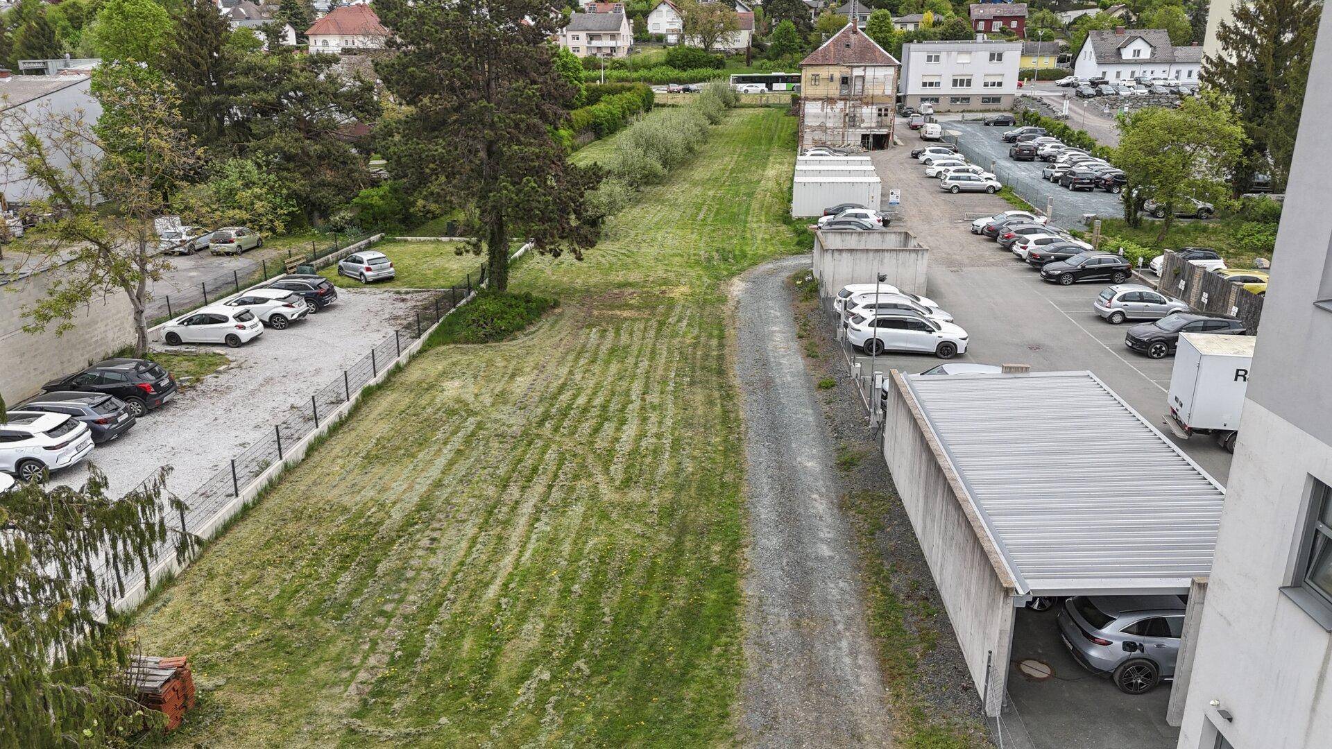 Luftaufnahme eines großen Außenbereichs mit Parkplätzen und einer Grünfläche.