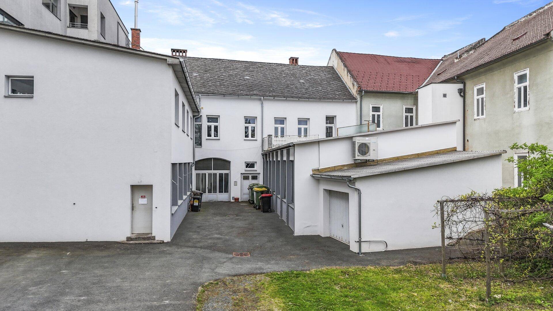 Luftaufnahme eines Gebäudekomplexes mit Innenhof und angrenzender Grünfläche.