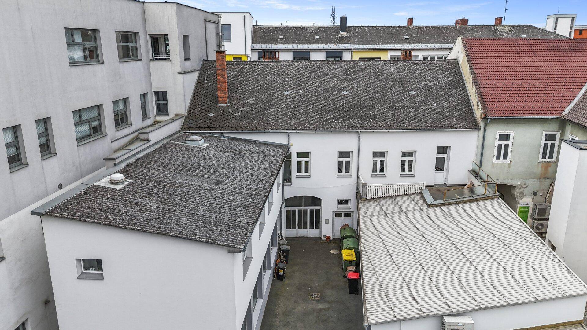 Luftaufnahme eines Gebäudekomplexes mit Innenhof und umliegenden Gebäuden.