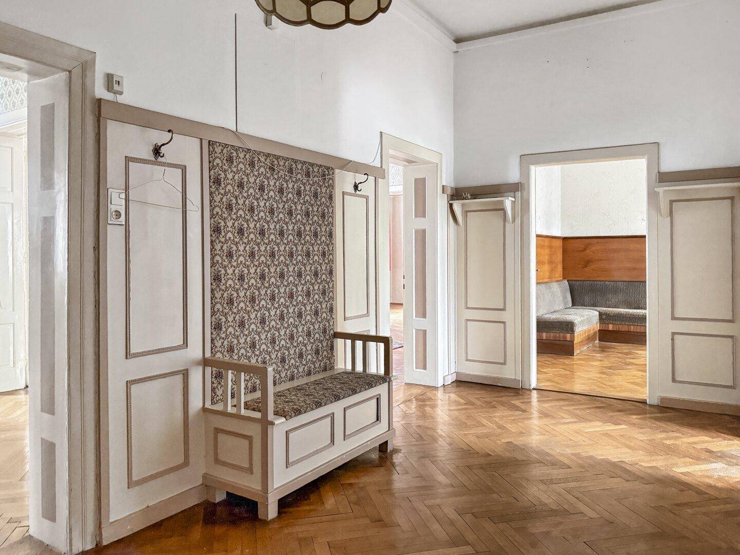 Geräumiger Flur mit Holzboden, hohen Decken und einer eingebauten Sitzbank mit Garderobe.