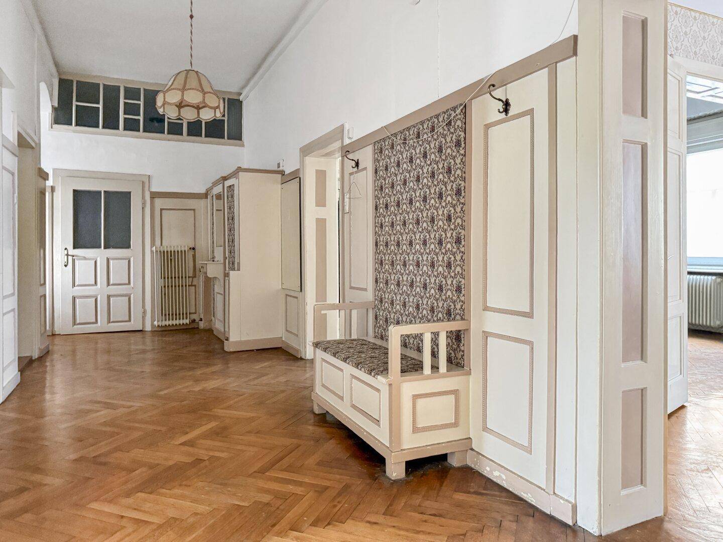 Geräumiger Flur mit Holzboden, hohen Decken und einer eingebauten Sitzbank mit Garderobe.