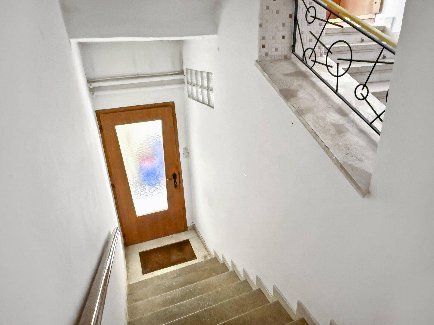 Treppenhaus mit Marmorstufen und einem Geländer im Vintage-Stil, das in die obere Etage führt.