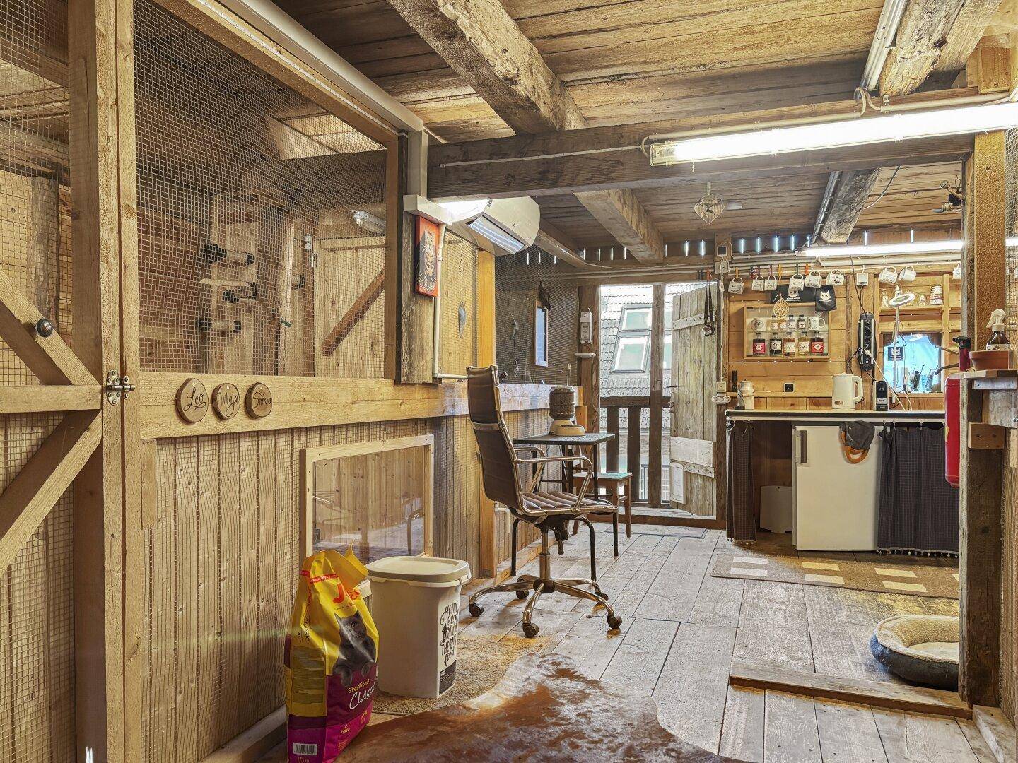 Rustikaler Raum mit Holzböden und -wänden, ausgestattet mit einer kleinen Küchenzeile und Arbeitsbereich.