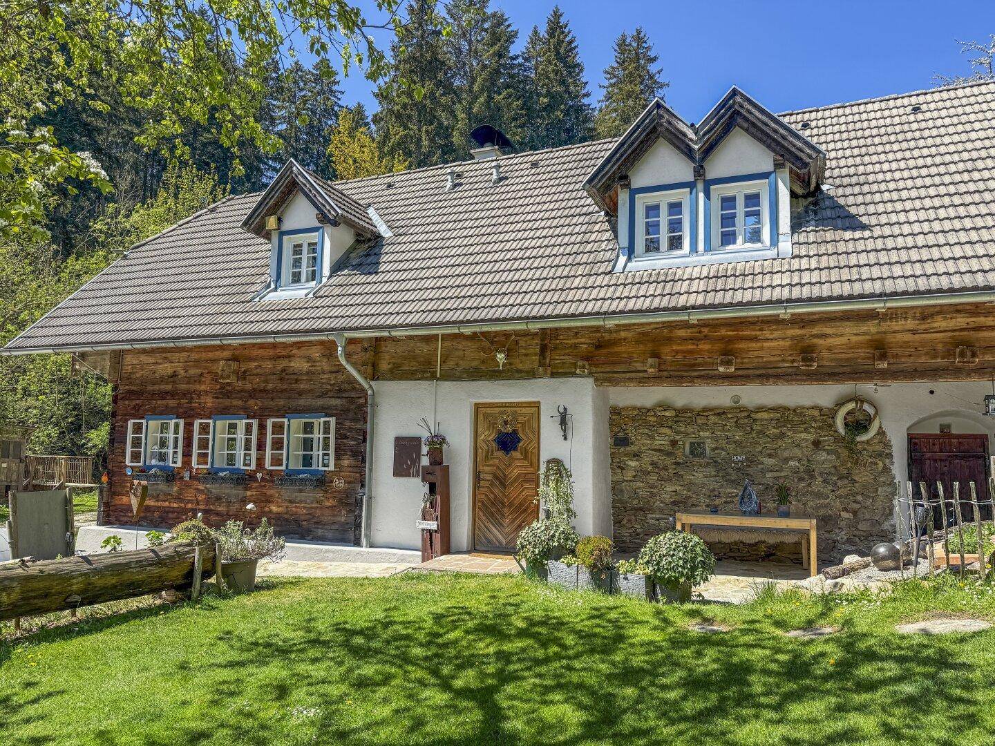 Charmantes Holzhaus mit traditionellen Gauben und gepflegtem Vorgarten in sonniger Lage.