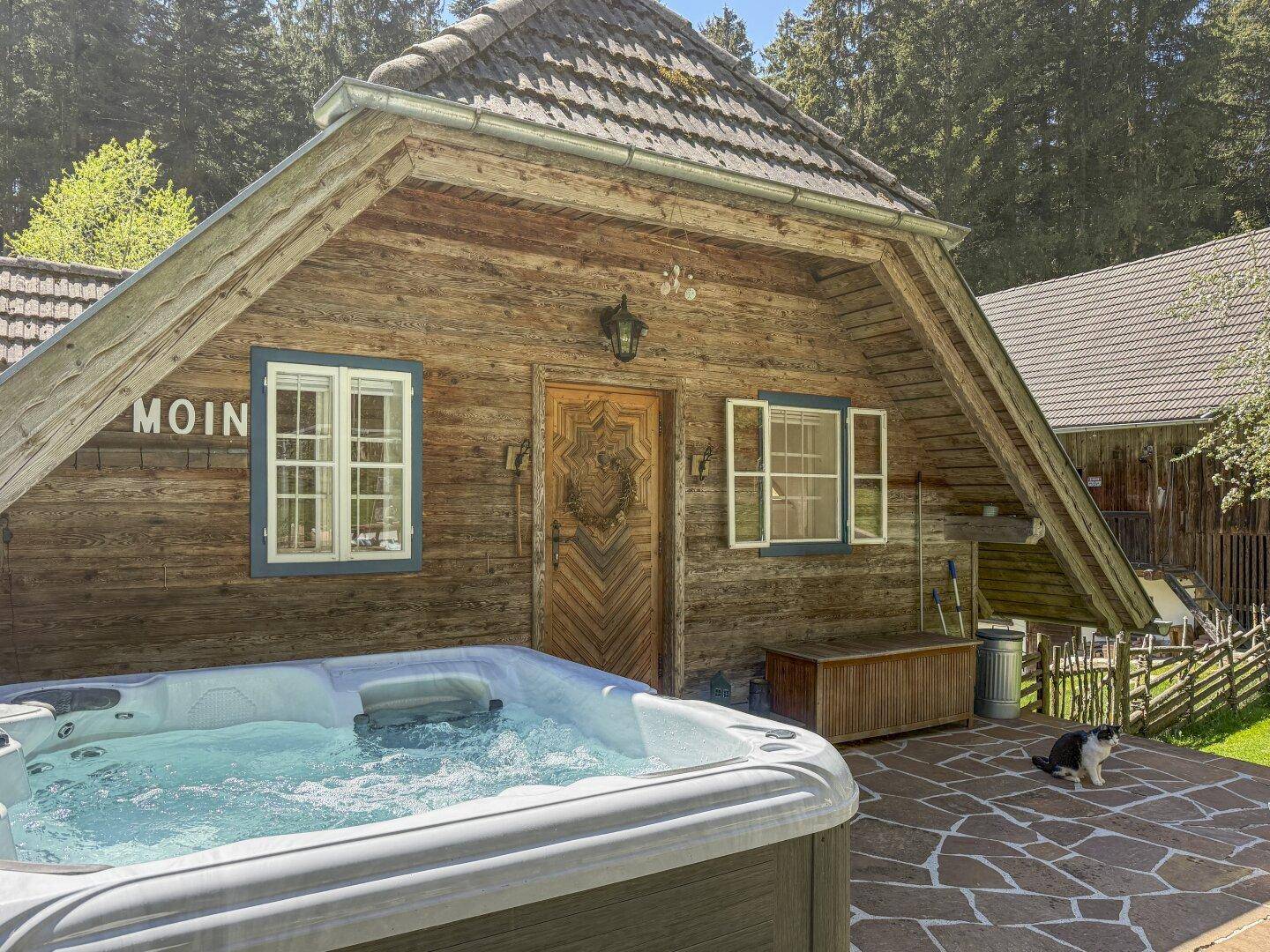 Nahaufnahme des sprudelnden Whirlpools auf der Steinterrasse vor dem charmanten Holzhaus.