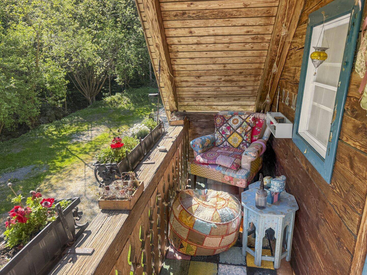Kleiner, liebevoll dekorierter Balkon mit bequemen Sitzgelegenheiten und Blick ins Grüne.